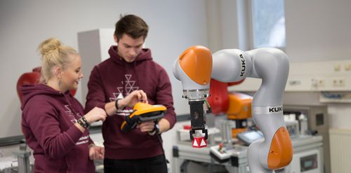 Studierende bedienen einen Industrieroboter
