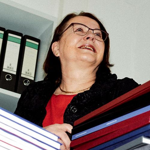 Sabine Elfring, Professorin für Betriebswirtschaftslehre, vor einem großen Stapel mit betreuten Abschlussarbeiten